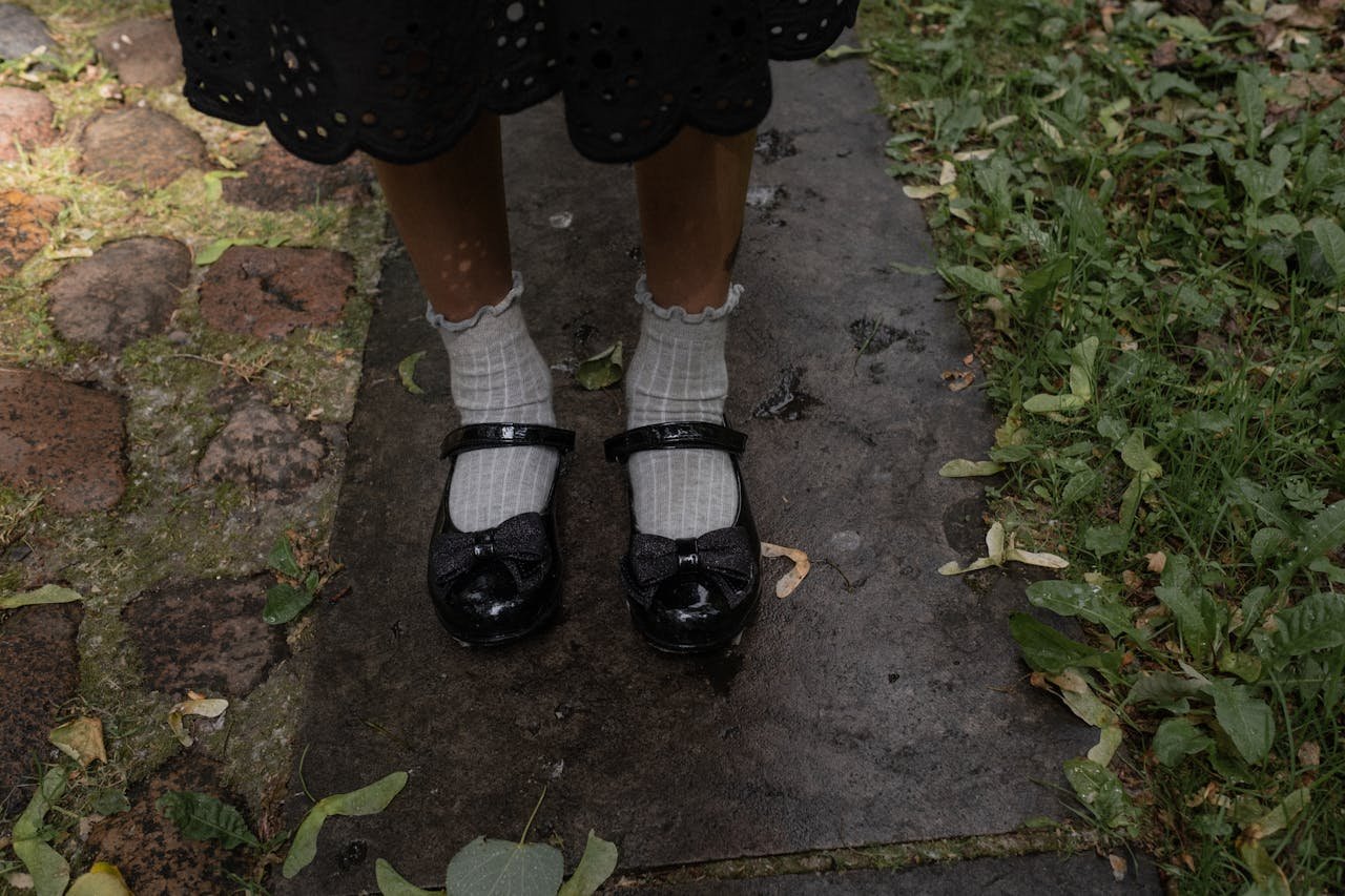 Close-up of a young girls patent leather shoes and white socks on a garden path.