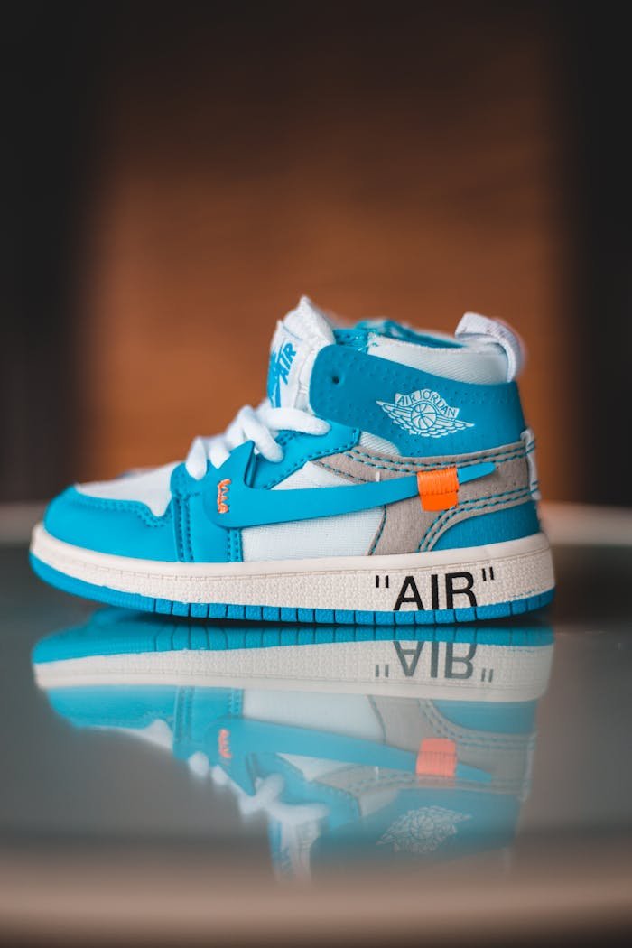 Mastering the First Impression: Your intriguing post title goes here Vibrant blue sneakers with white laces reflecting on a glossy surface, showcasing modern footwear design.
